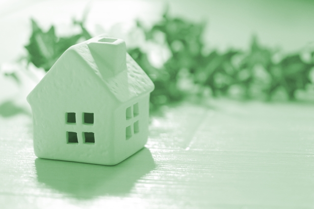 白いフローリングの上に家の模型とフェイクグリーンが置かれている画像